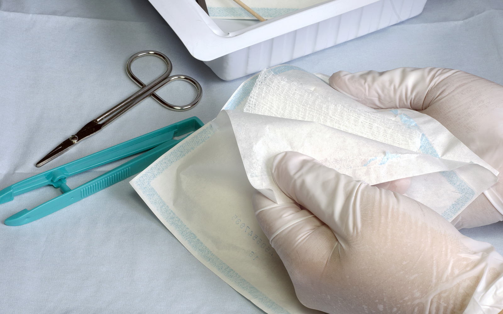 Wound bandages showing a person wearing gloves and opening a bandage for wound care.